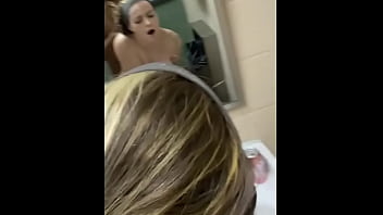 Long-haired girl moans and orgasms during public bathroom encounter